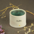 a small ceramic pot, hand decoarated and glazed with a word from a poem