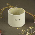 a small ceramic pot, hand decoarated and glazed with a word from a poem
